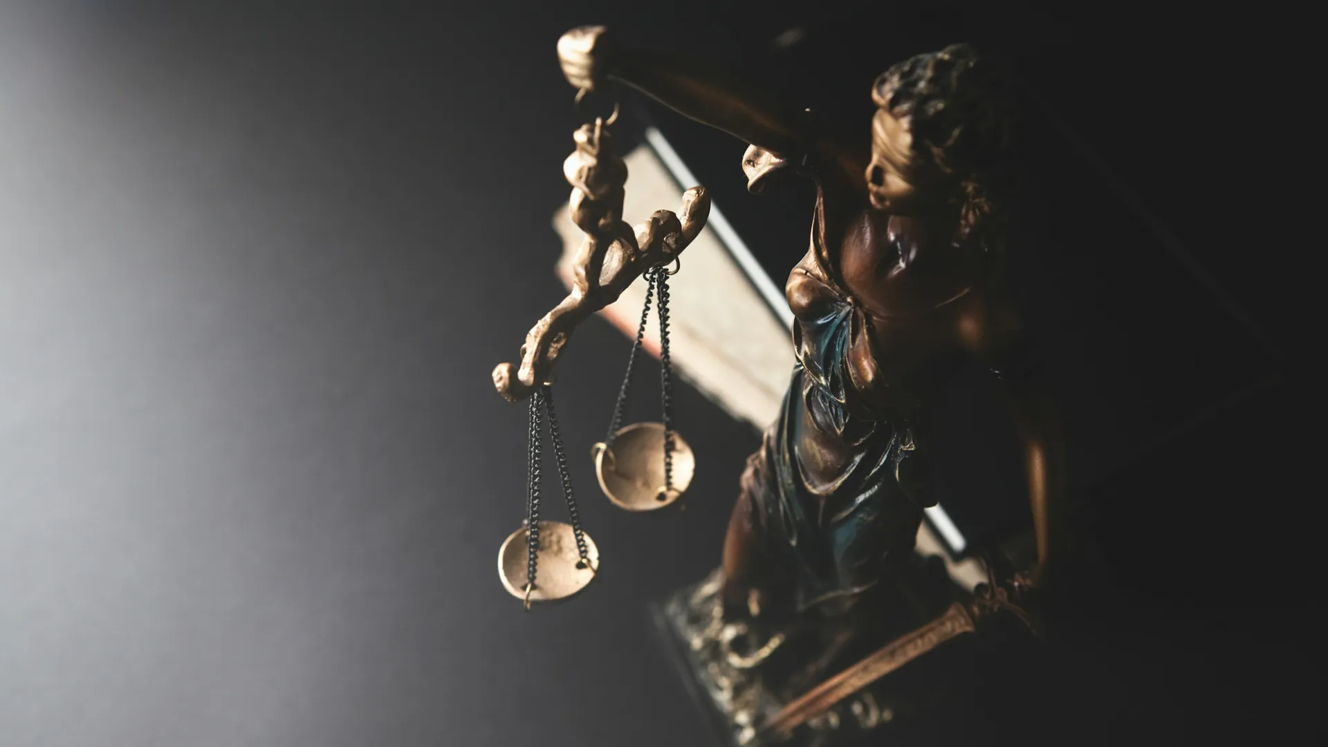 Justitia-Statue mit Waage vor dunklem Hintergrund